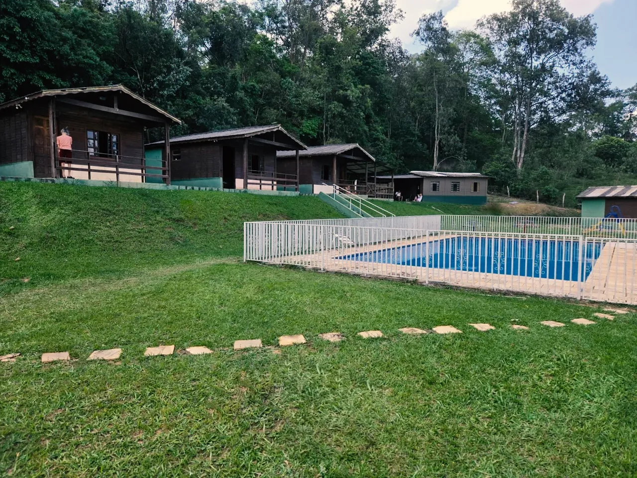Fachada dos chalés da VilaCare cercados por árvores e gramado em Atibaia